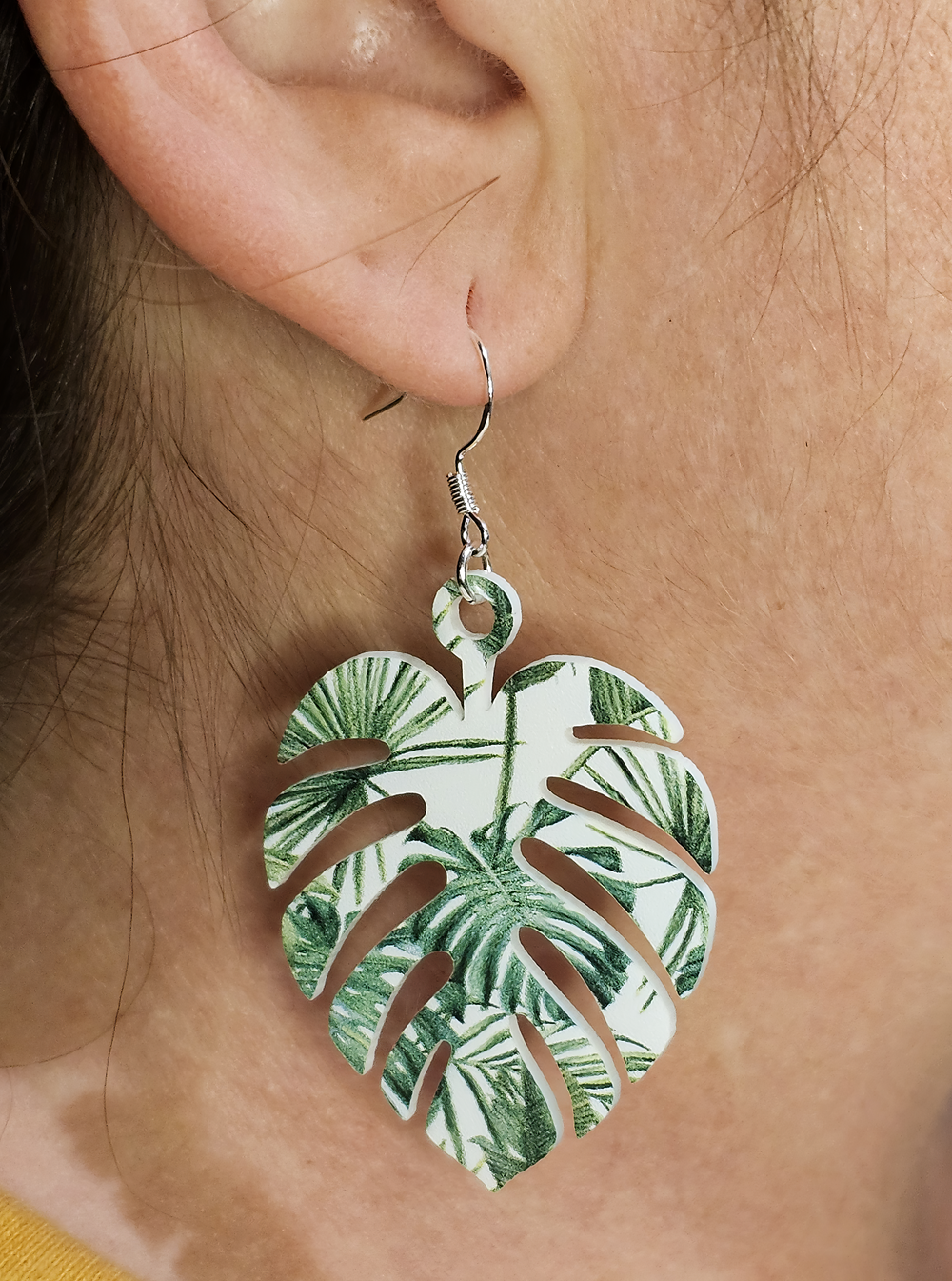 Monstera leaf acrylic earring with green tropical print shown worn on ear.
