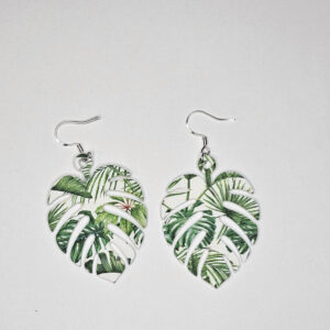Acrylic monstera leaf earrings with green tropical foliage pattern on white background.